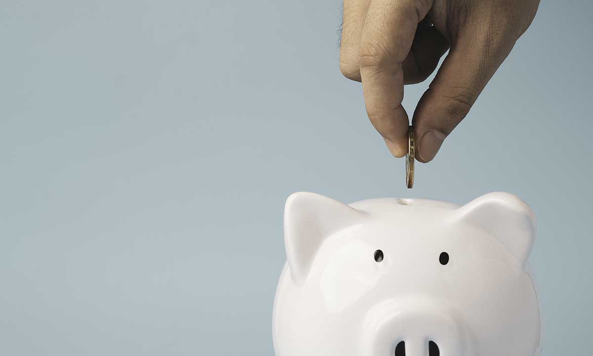 Person putting coin in piggy bank