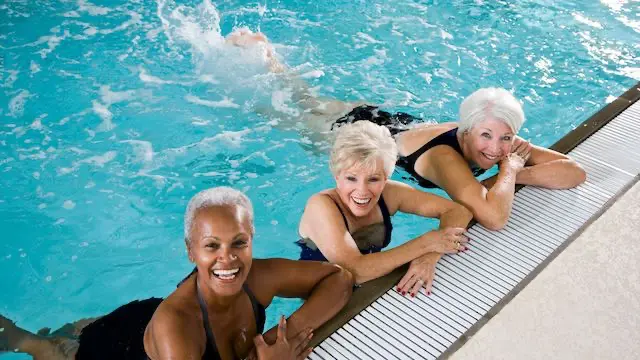 Women with gray hair floating on side of pool