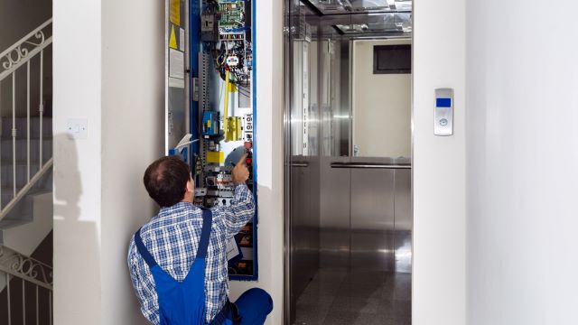 Technician servicing elevator in high rise HOA community